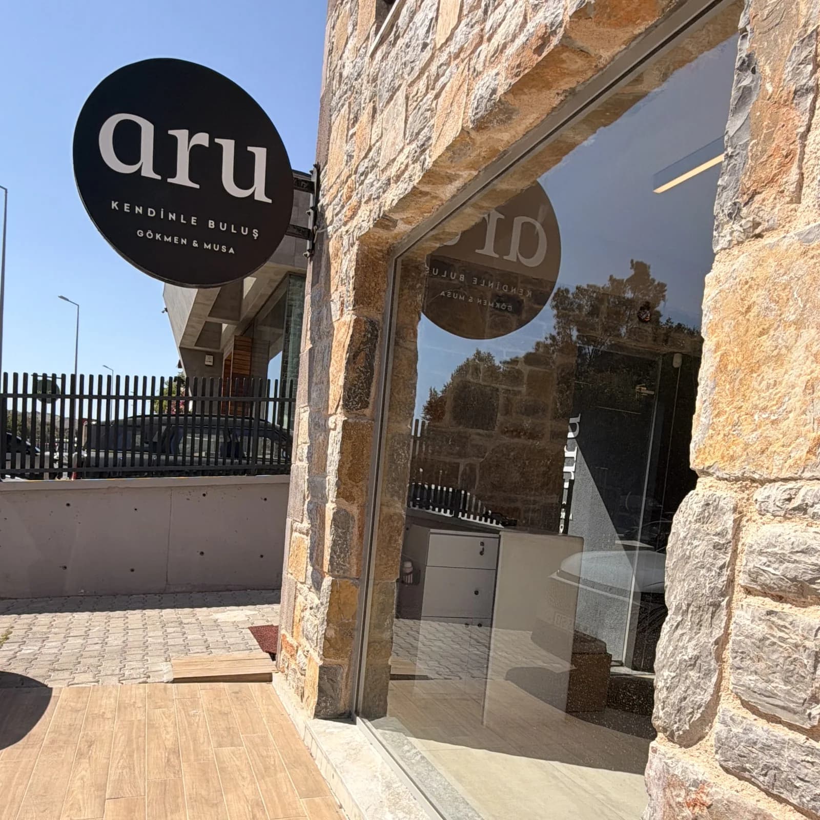 aru Bodrum salonunun dış cephesi: taş duvara asılı yuvarlak aru tabelası ve vitrin